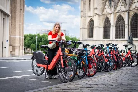 Personne qui déverrouille un vélo Voi dans une dropzone où se trouvent aussi des Dott et Bolt